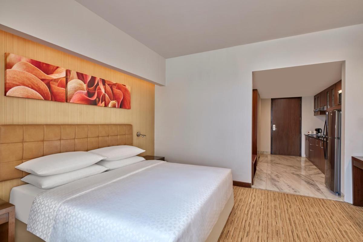 a bedroom with a white bed and a painting on the wall at Four Points by Sheraton Hotel and Serviced Apartments Pune in Pune