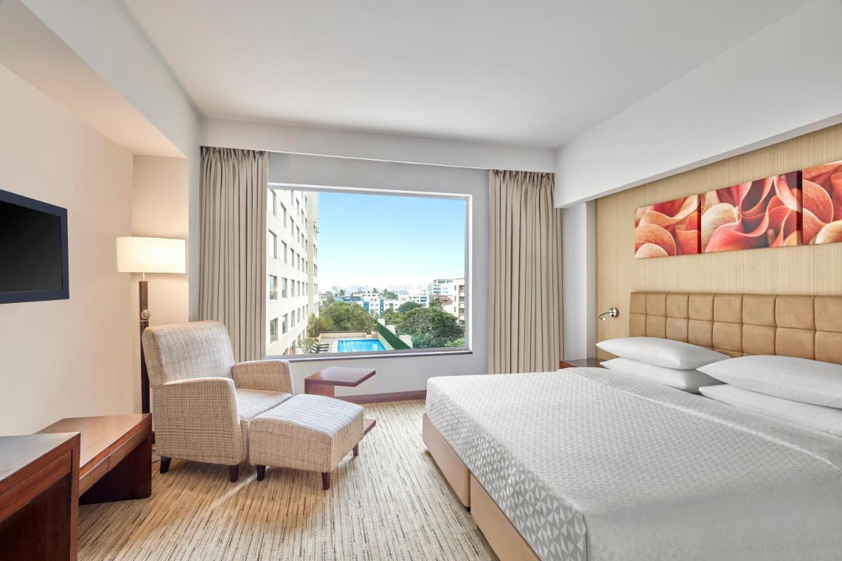 a hotel room with a bed and a large window at Four Points by Sheraton Hotel and Serviced Apartments Pune in Pune