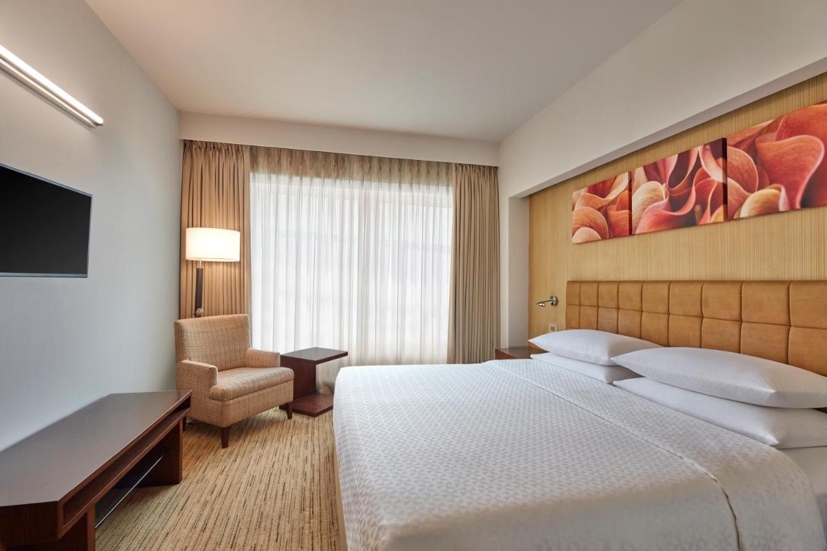 a hotel room with a large bed and a chair at Four Points by Sheraton Hotel and Serviced Apartments Pune in Pune