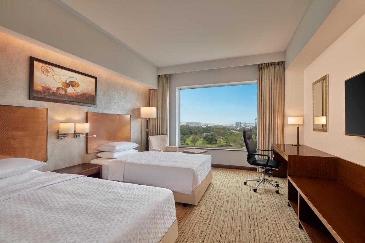 a hotel room with two beds and a large window at Four Points by Sheraton Hotel and Serviced Apartments Pune in Pune