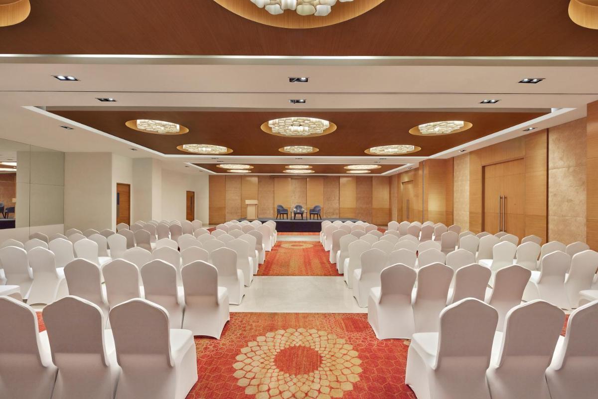 an empty conference room with white chairs and a stage at Four Points by Sheraton Hotel and Serviced Apartments Pune in Pune