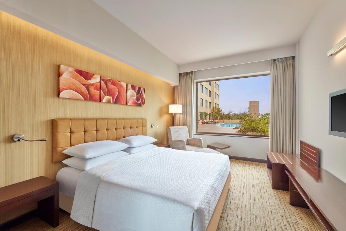 a hotel room with a bed and a large window at Four Points by Sheraton Hotel and Serviced Apartments Pune in Pune