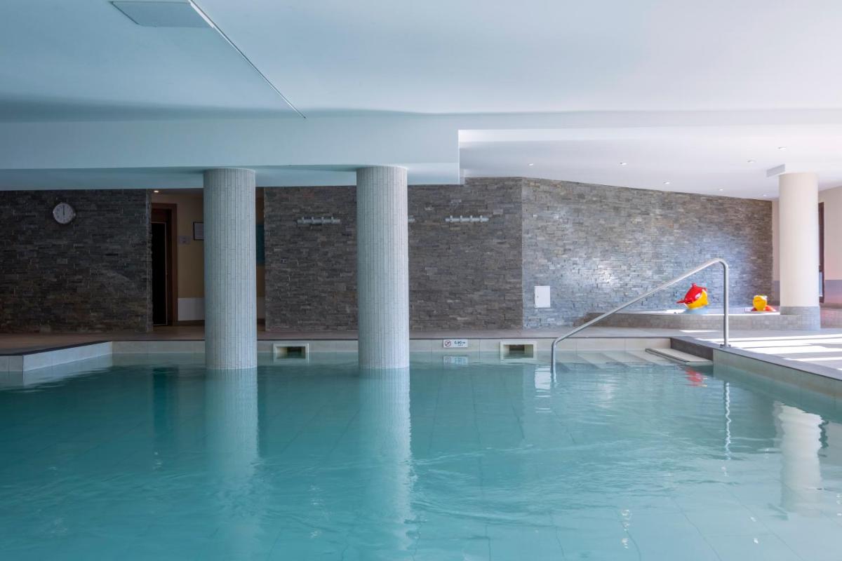 - une piscine avec une fontaine dans un bâtiment dans l'établissement Résidence Pierre & Vacances Premium Les Terrasses d'Hélios, à Flaine