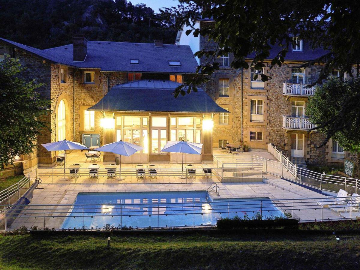 un bâtiment avec une piscine devant un bâtiment dans l'établissement Mercure Saint Nectaire - Spa & Bien-Être, à Saint-Nectaire