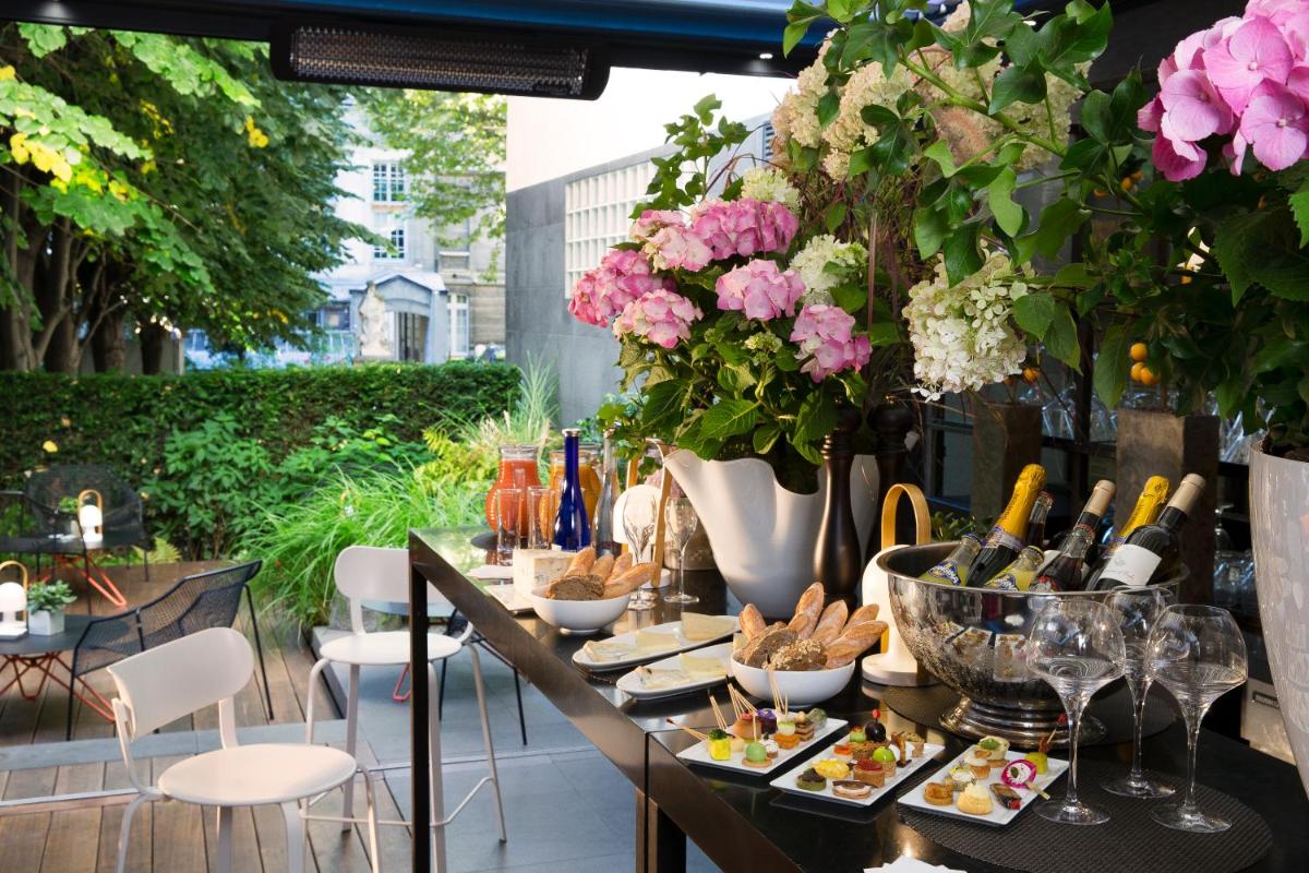 une table avec de la nourriture, des bouteilles de vin et des fleurs dans l'établissement Hotel & Spa La Belle Juliette, à Paris
