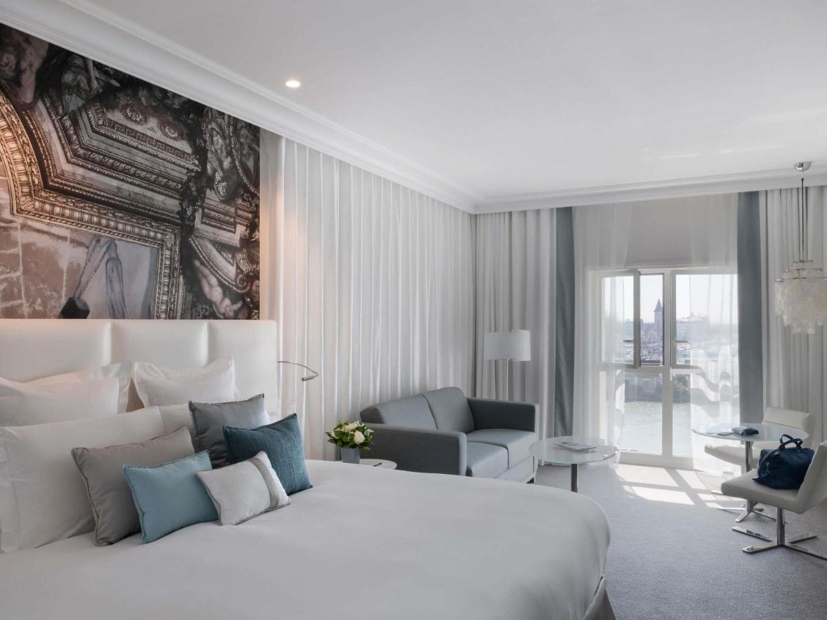 une chambre avec un grand lit blanc et une chaise dans l'établissement Cures Marines Hotel Thalasso & Spa Trouville - MGallery Collection, à Trouville-sur-Mer