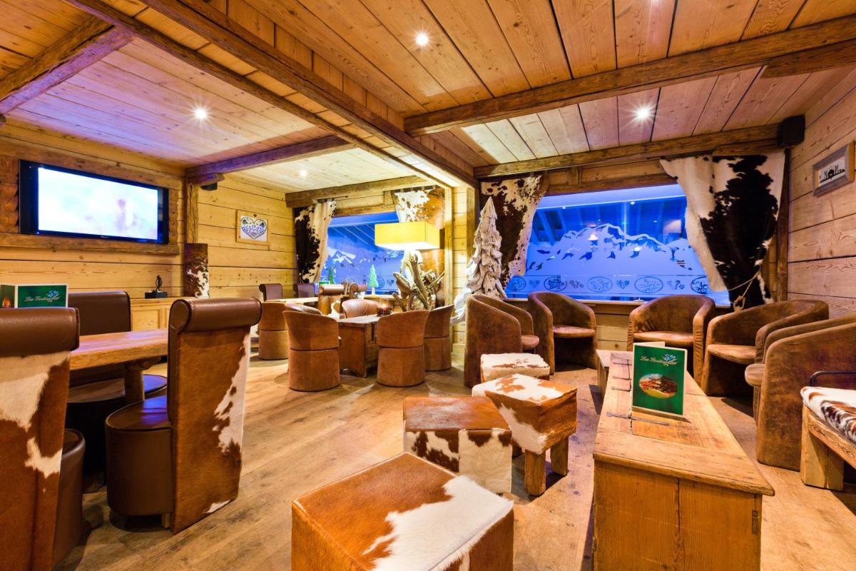 une pièce avec des chaises et des tables et une grande fenêtre dans l'établissement Les Gentianettes Hotel & Spa, à La Chapelle-dʼAbondance
