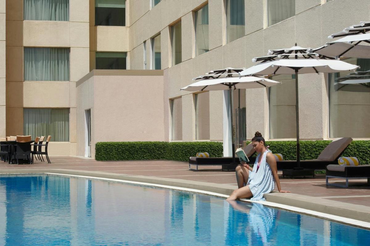 a man and woman sitting next to a swimming pool at Four Points by Sheraton Hotel and Serviced Apartments Pune in Pune