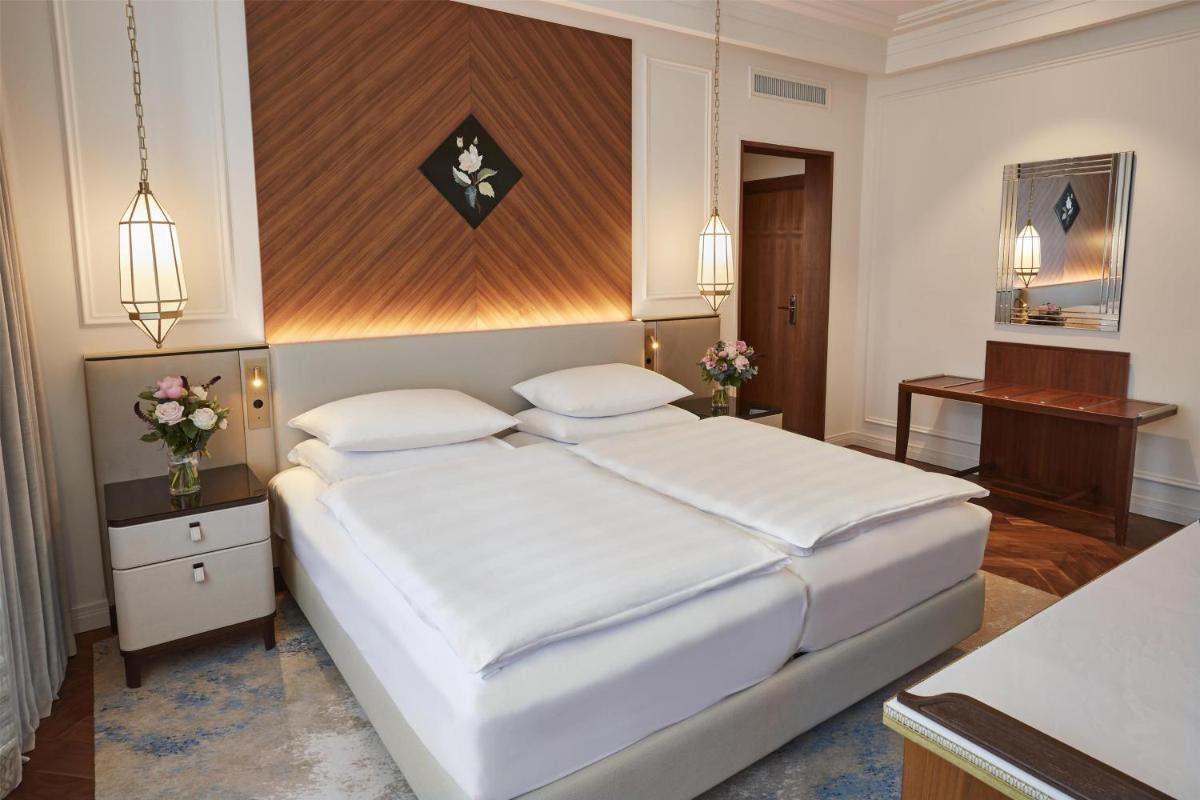 ein Schlafzimmer mit einem großen weißen Bett in einem Zimmer in der Unterkunft Vier Jahreszeiten Kempinski München in München