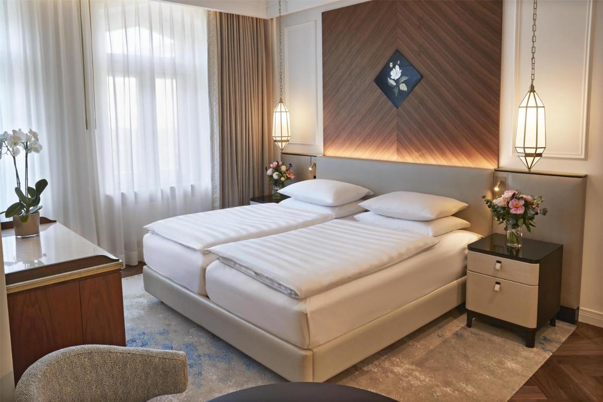 ein Schlafzimmer mit einem großen weißen Bett in einem Zimmer in der Unterkunft Vier Jahreszeiten Kempinski München in München