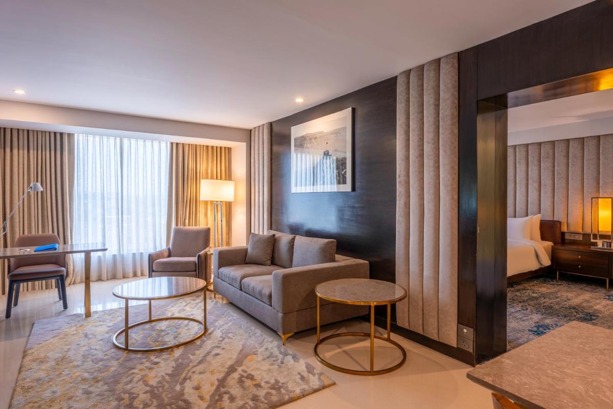 a hotel room with a couch and tables and a bed at Radisson Blu Hotel Pune Kharadi in Pune