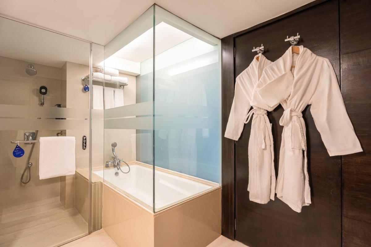 a bathroom with a shower and a robe hanging on a door at Radisson Blu Hotel Pune Kharadi in Pune
