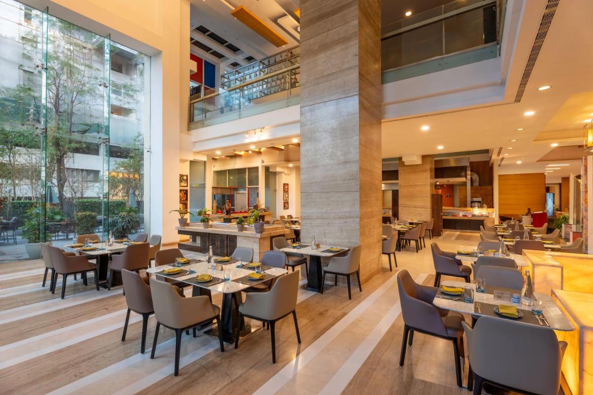 a restaurant with tables and chairs and large windows at Radisson Blu Hotel Pune Kharadi in Pune