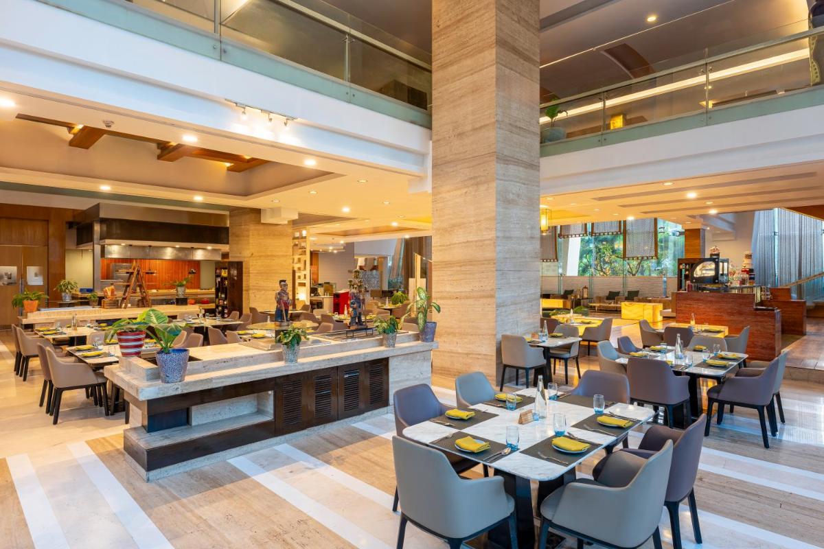 a restaurant with tables and chairs and a bar at Radisson Blu Hotel Pune Kharadi in Pune