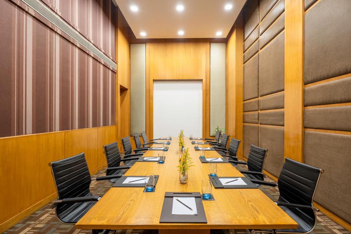 a conference room with a long wooden table and chairs at Radisson Blu Hotel Pune Kharadi in Pune