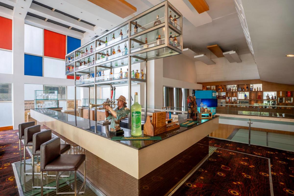 a bar in a restaurant with a person sitting at it at Radisson Blu Hotel Pune Kharadi in Pune