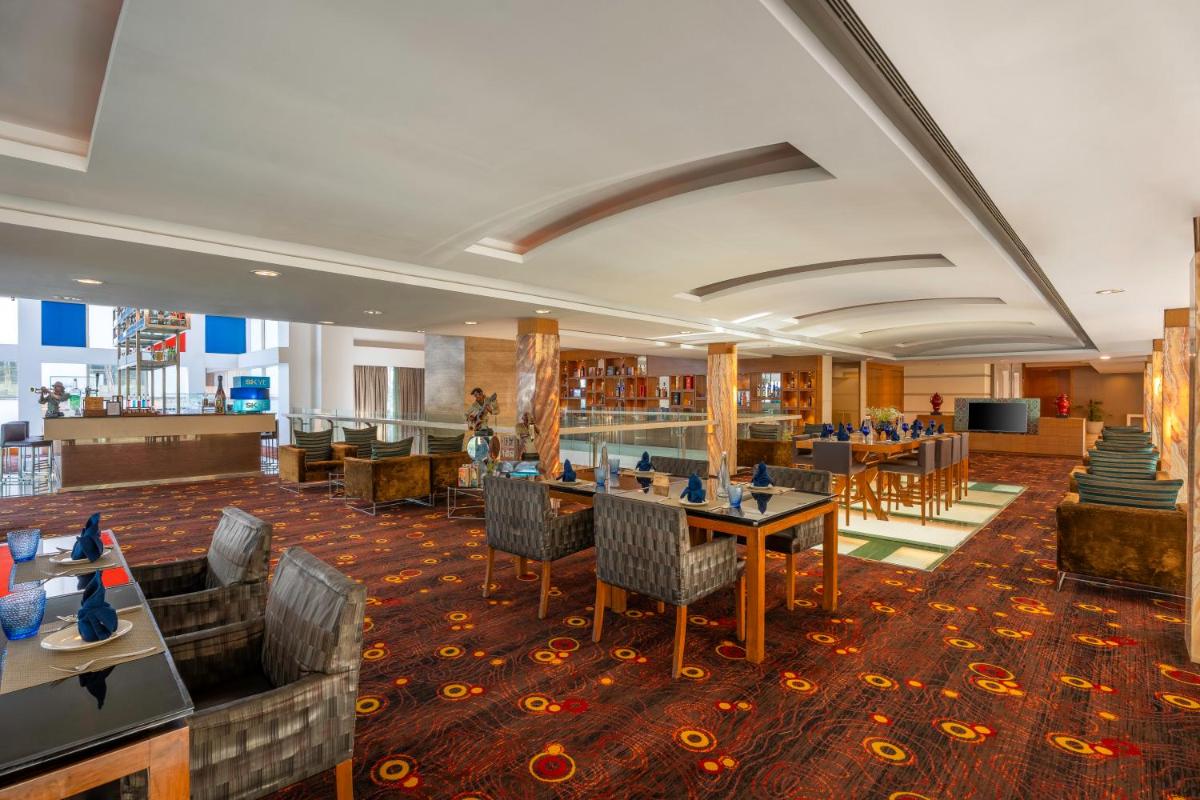 a hotel lobby with tables and chairs and a bar at Radisson Blu Hotel Pune Kharadi in Pune