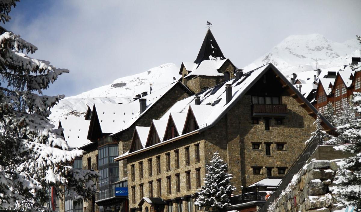 un edificio cubierto de nieve con una montaña en el fondo en Snö Villa de Sallent 4, en Formigal