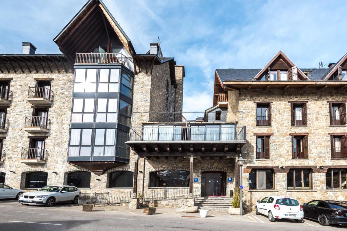 un gran edificio de piedra con coches estacionados frente a él en Snö Villa de Sallent 4, en Formigal