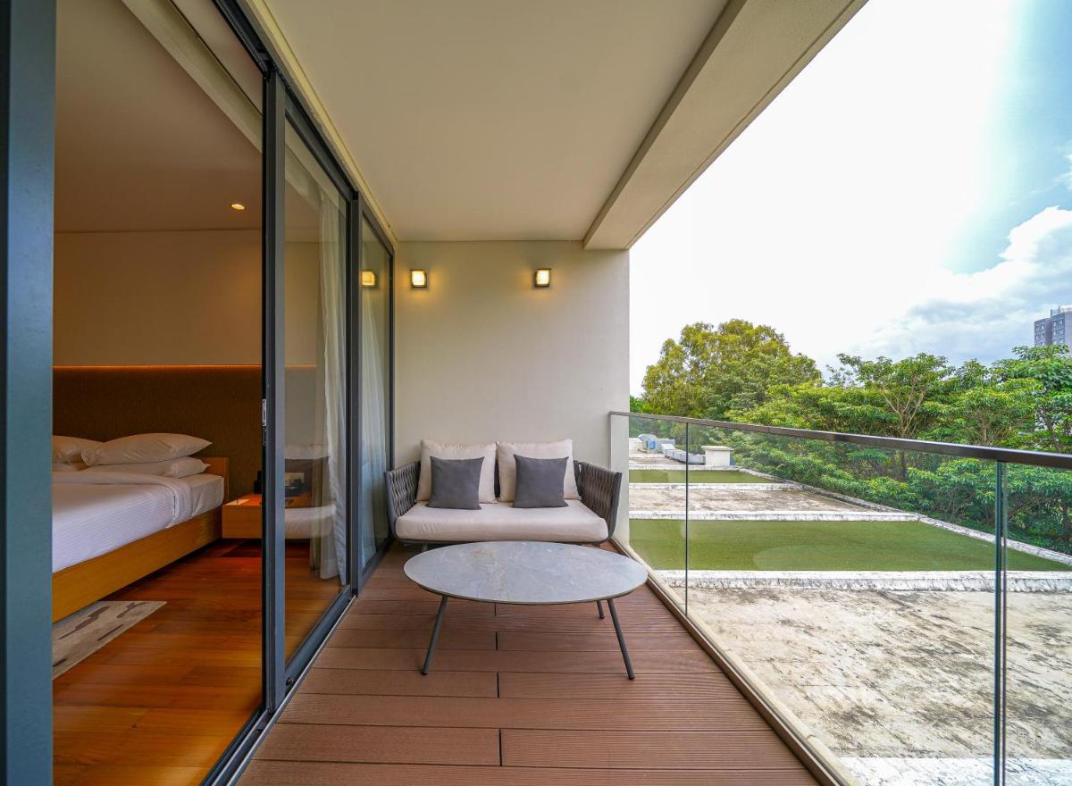 a bedroom with a balcony with a bed and a table at BLVD Club - Near BENGALURU AIRPORT in Bengaluru