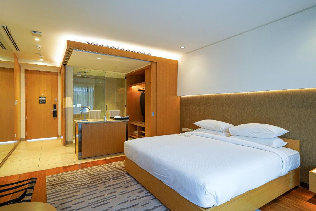 a bedroom with a large bed and a bathroom at BLVD Club - Near BENGALURU AIRPORT in Bengaluru
