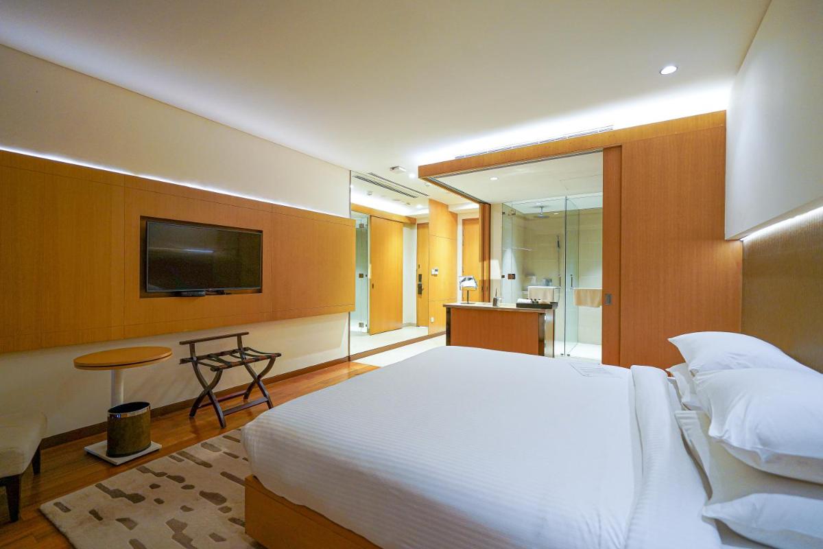 a bedroom with a large white bed and a television at BLVD Club - Near BENGALURU AIRPORT in Bengaluru