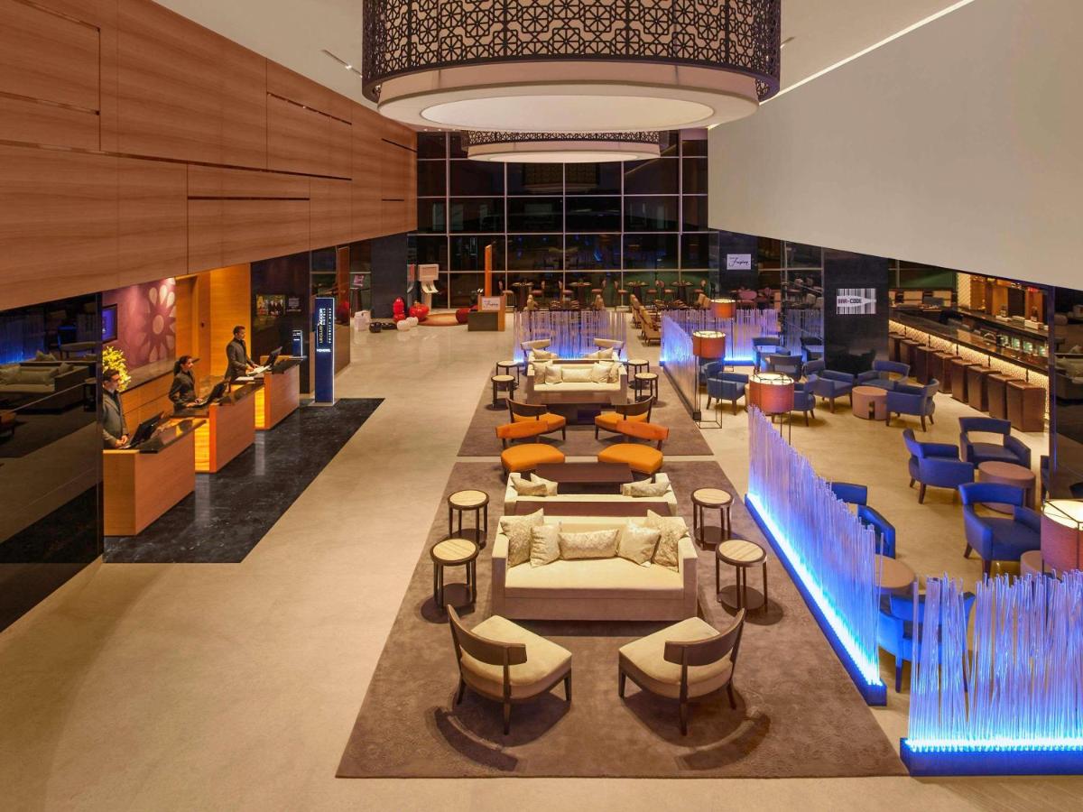 a library with blue chairs and tables in a building at Novotel Pune Viman Nagar Road in Pune