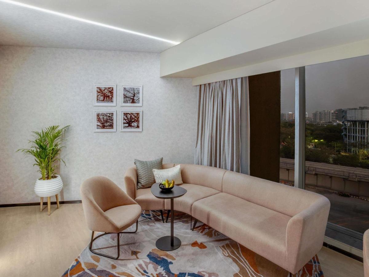 a living room with a couch and a table and chairs at Novotel Pune Viman Nagar Road in Pune