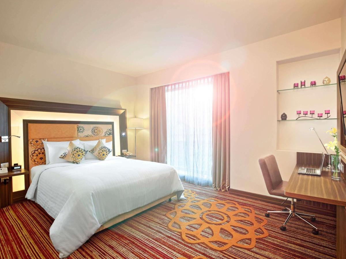 a hotel room with a bed and a desk and a computer at Novotel Pune Viman Nagar Road in Pune