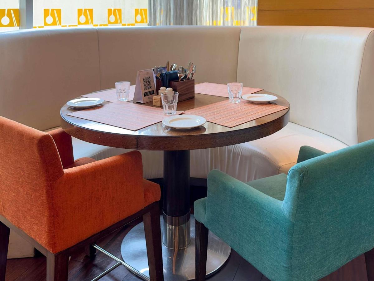 a table in a restaurant with two chairs at Novotel Pune Viman Nagar Road in Pune