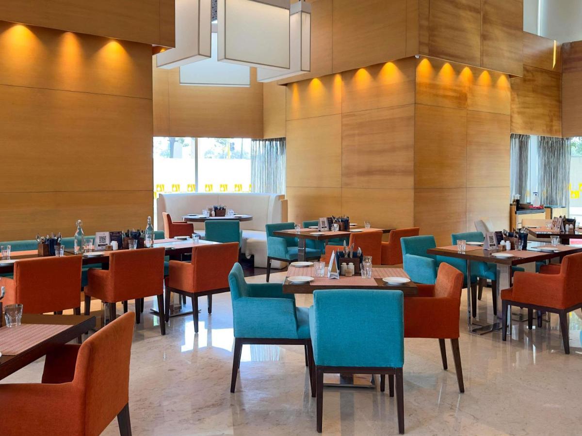 a dining room with tables and chairs in a restaurant at Novotel Pune Viman Nagar Road in Pune