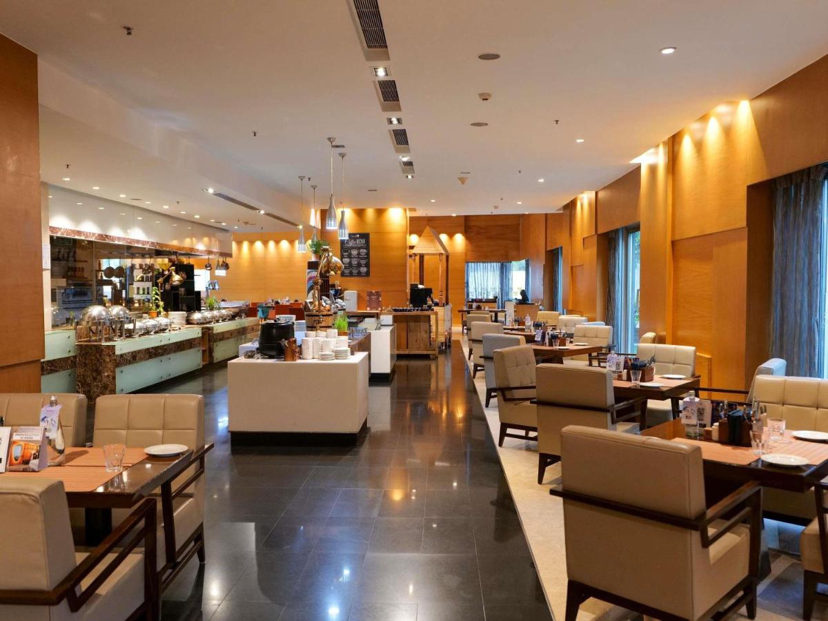 a restaurant with tables and chairs and a bar at Novotel Pune Viman Nagar Road in Pune