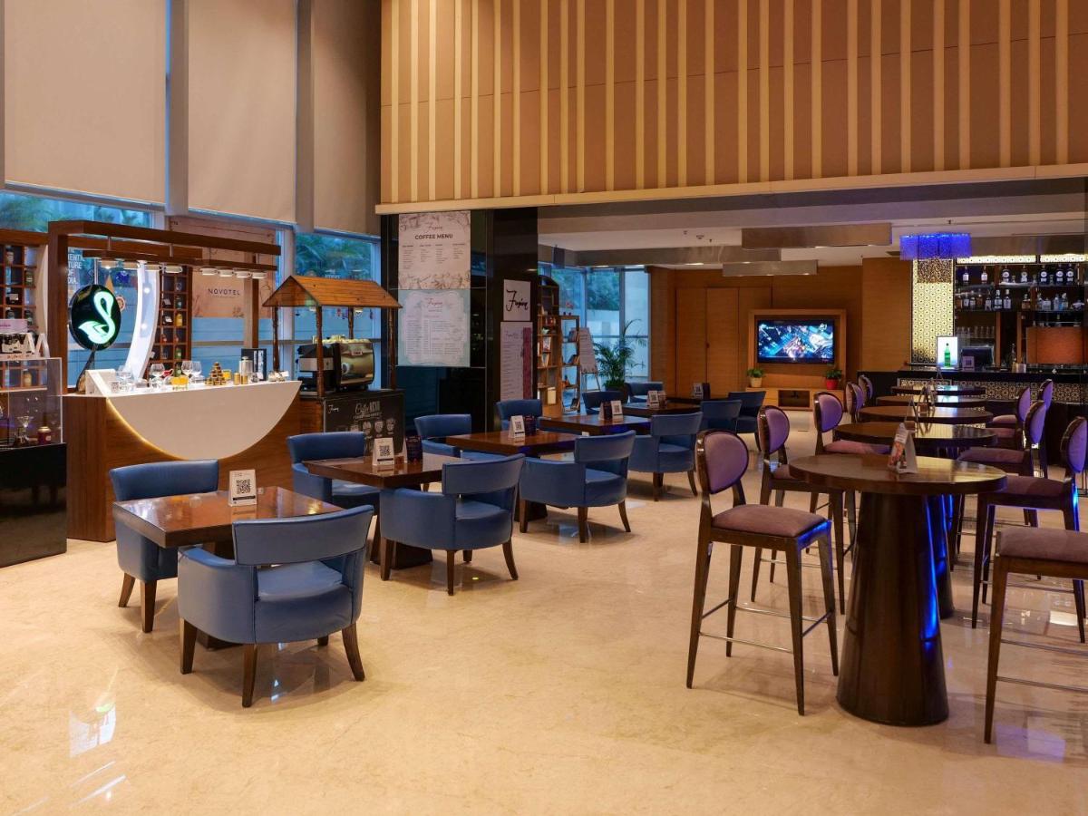 a restaurant with tables and chairs and a bar at Novotel Pune Viman Nagar Road in Pune