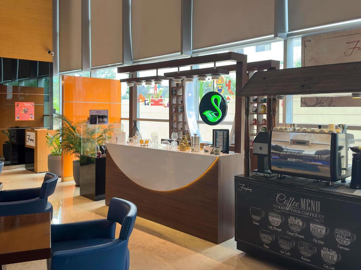 a restaurant with a counter with a bar in it at Novotel Pune Viman Nagar Road in Pune