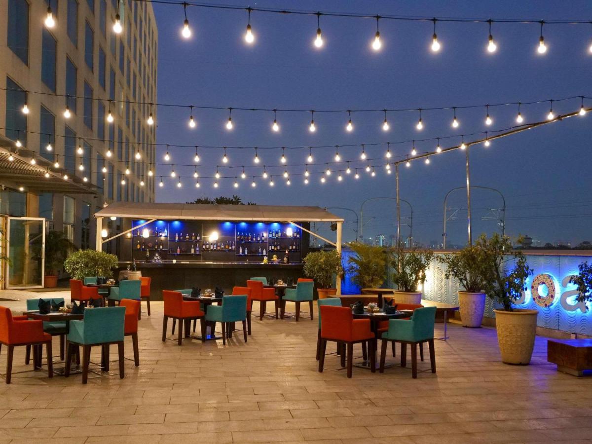 a restaurant with tables and chairs and lights at Novotel Pune Viman Nagar Road in Pune