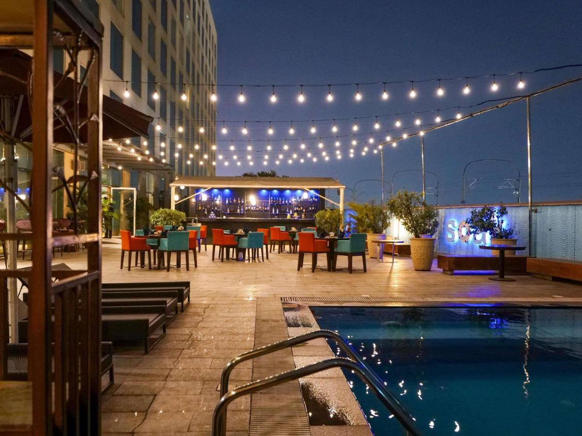 a patio with a pool and a bar with lights at Novotel Pune Viman Nagar Road in Pune
