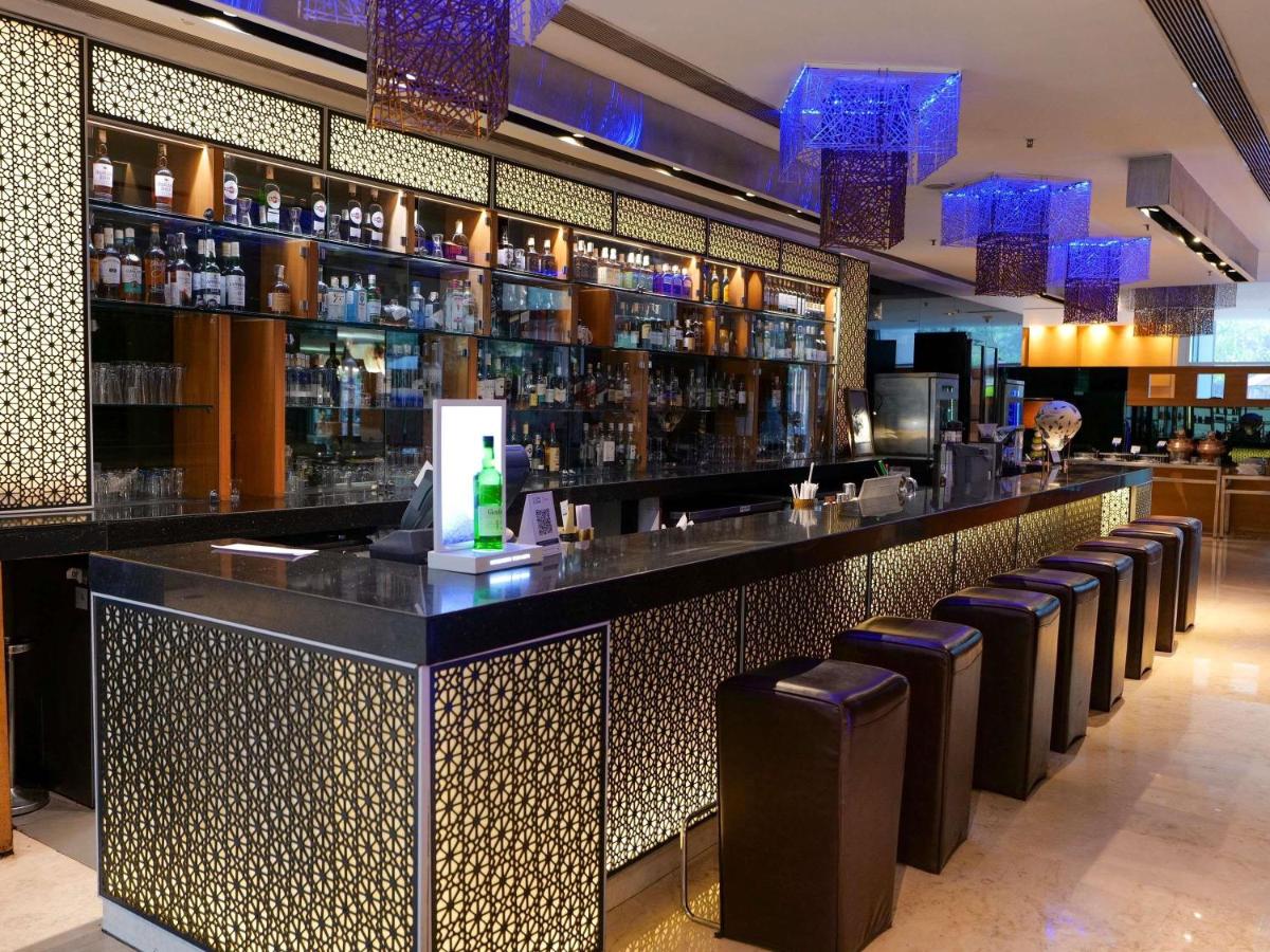 a bar with a row of stools in a restaurant at Novotel Pune Viman Nagar Road in Pune