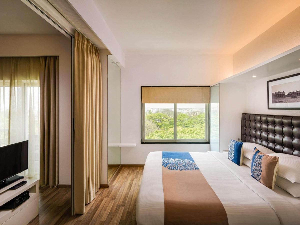 a hotel room with a large bed and a window at Grand Mercure Bangalore - An Accor Brand in Bengaluru