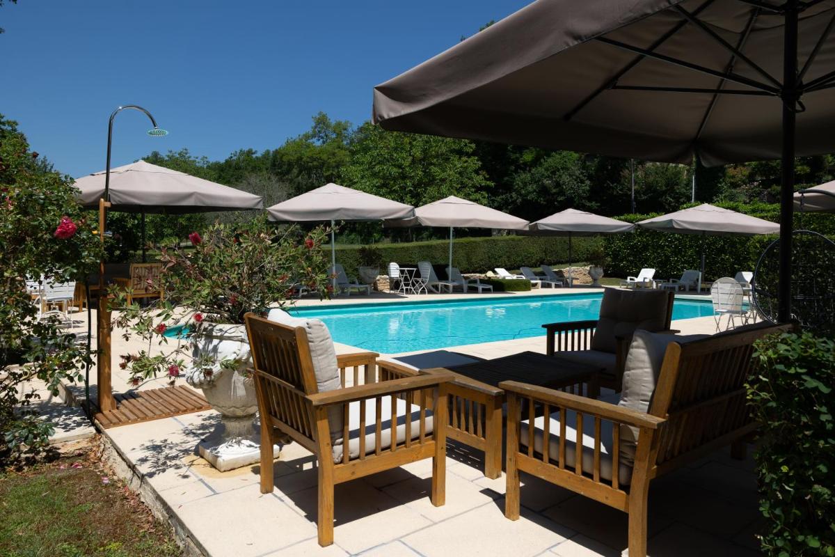 une piscine avec deux chaises longues et un parasol dans l'établissement Le Moulin de Mitou, à Auriac-du-Périgord