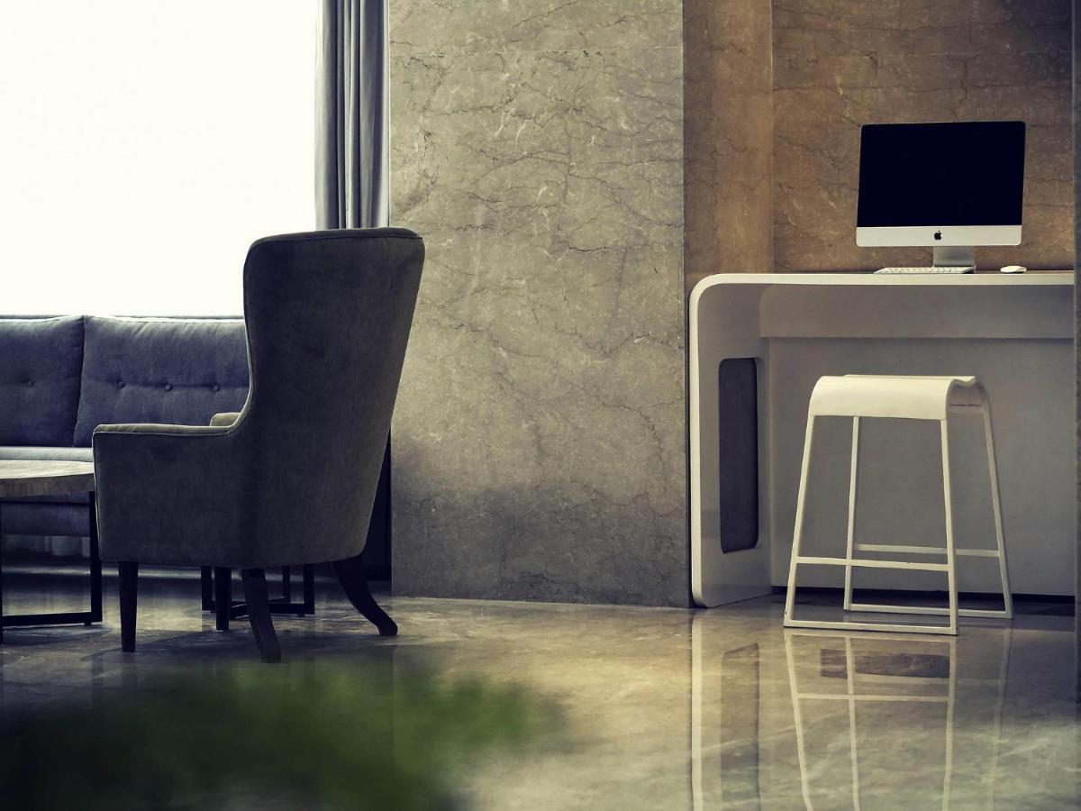 a living room with a chair and a computer on a desk at Mercure Hyderabad KCP Banjara Hills, An Accor Hotel in Hyderabad