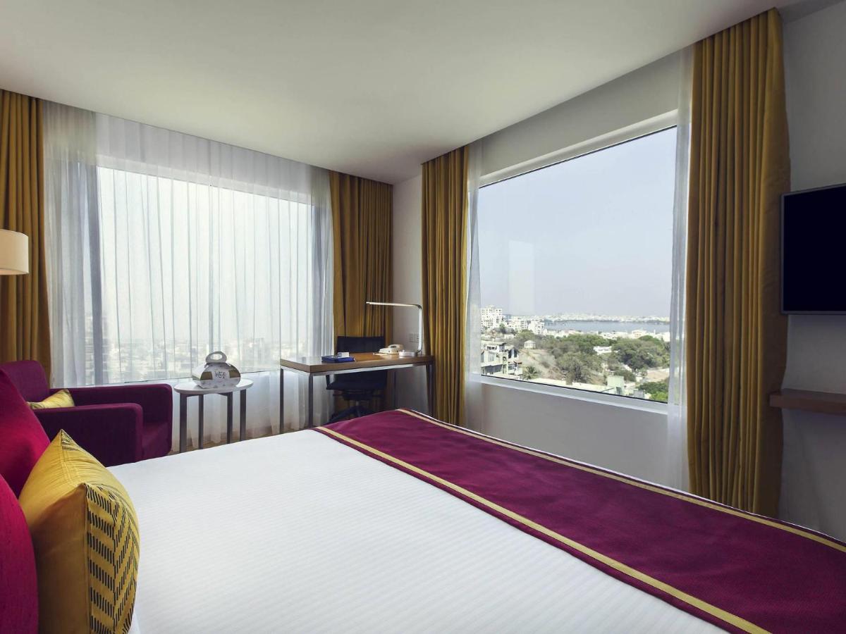 a hotel room with a bed and a large window at Mercure Hyderabad KCP Banjara Hills, An Accor Hotel in Hyderabad +91 photos