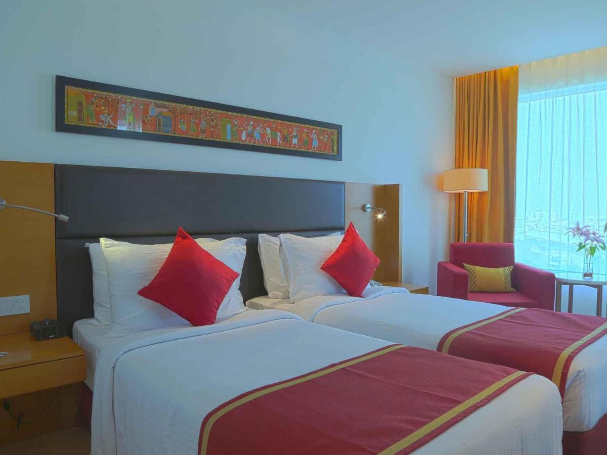 two beds in a hotel room with red and white pillows at Mercure Hyderabad KCP Banjara Hills, An Accor Hotel in Hyderabad