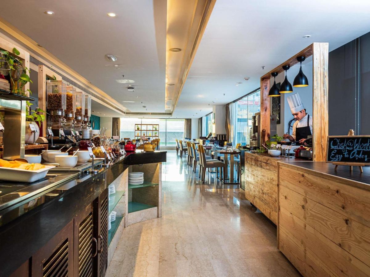 a restaurant with a bar with tables and chairs at Mercure Hyderabad KCP Banjara Hills, An Accor Hotel in Hyderabad