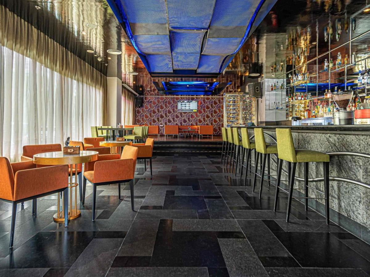 a restaurant with tables and chairs and a bar at Mercure Hyderabad KCP Banjara Hills, An Accor Hotel in Hyderabad