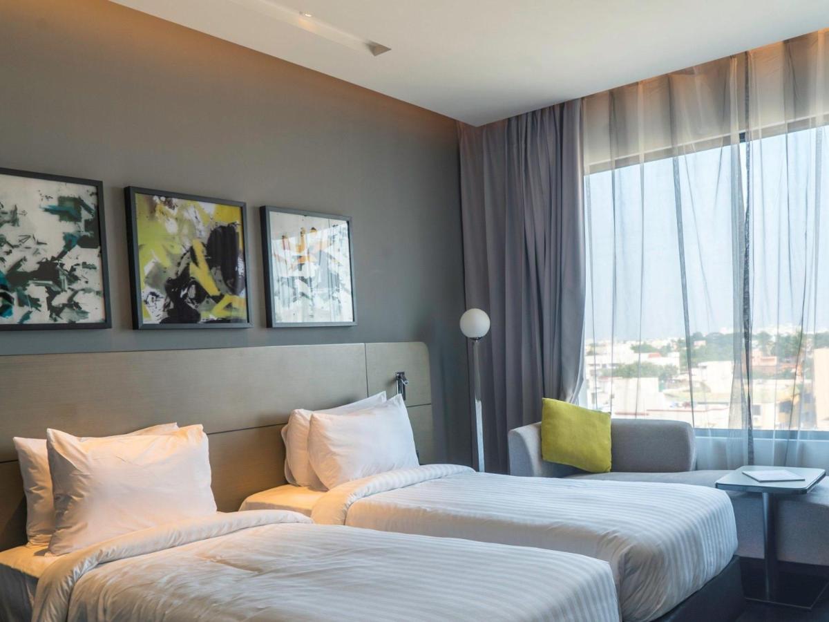 a hotel room with two beds and a window at Novotel Chennai Chamiers Road in Chennai