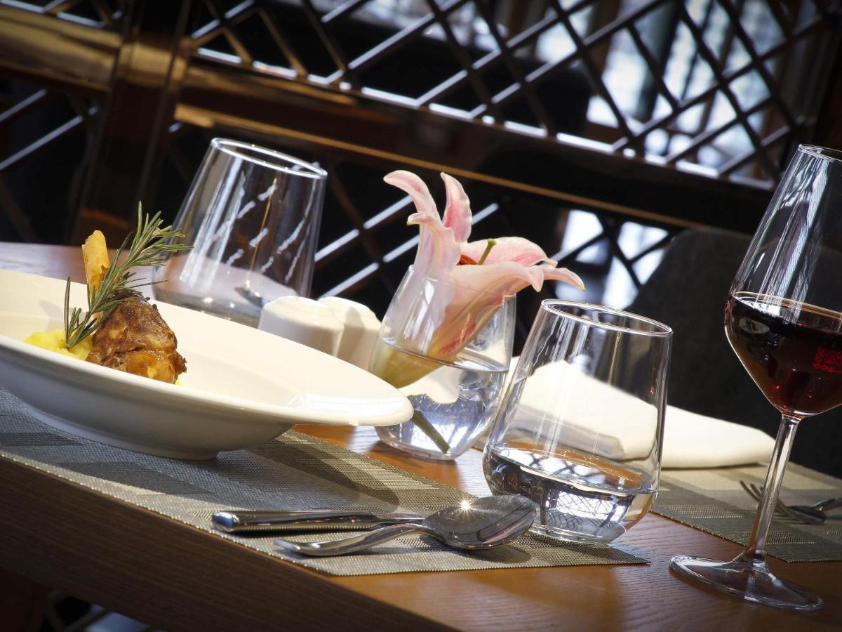 a table with a plate of food and wine glasses at Novotel Chennai Chamiers Road in Chennai