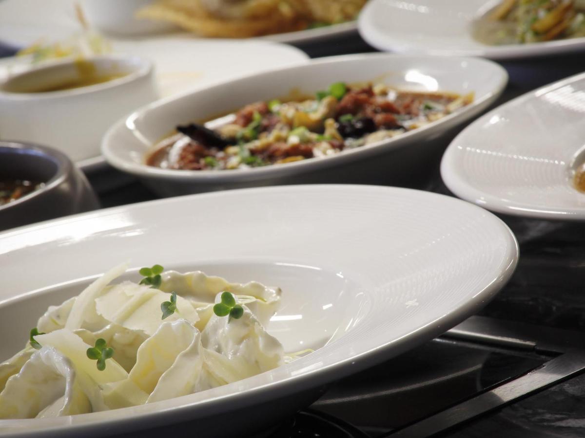 a white bowl of dumplings on a table with other dishes at Novotel Chennai Chamiers Road in Chennai