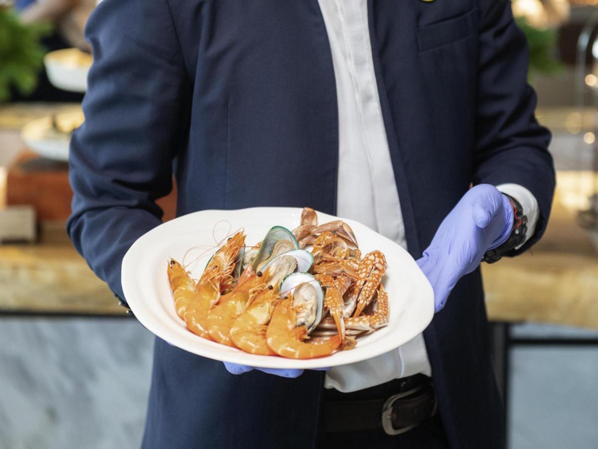 a man is holding a plate of seafood at Novotel Chennai Chamiers Road in Chennai