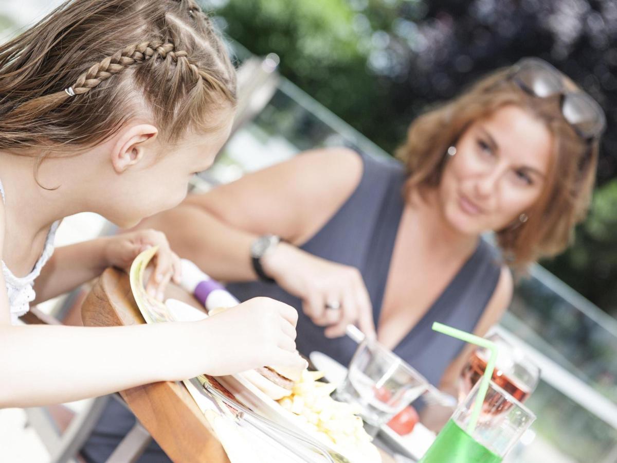 two women sitting at a table eating food at Novotel Chennai Chamiers Road in Chennai