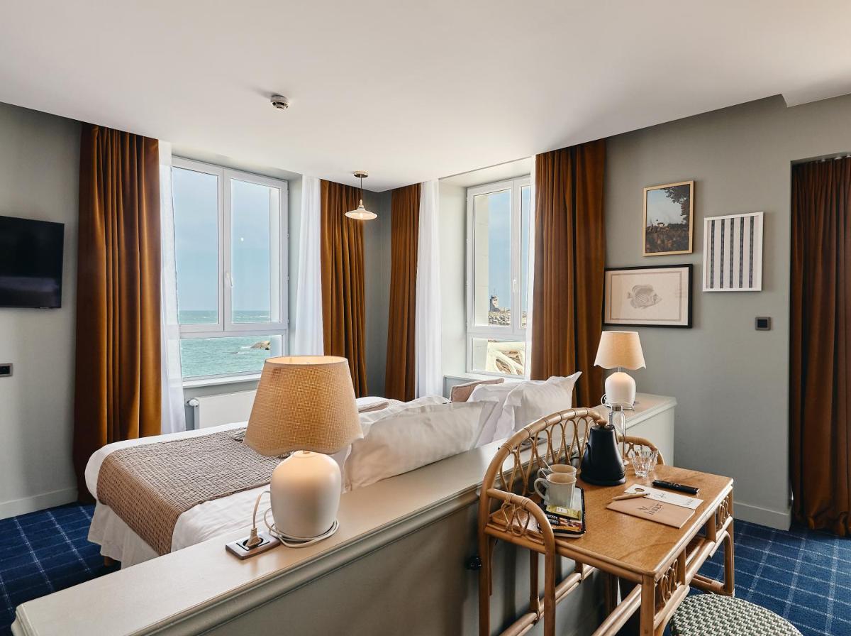 une chambre d'hôtel avec un lit, une table et des chaises dans l'établissement Hôtel de la Mer & Spa, à Brignogan-Plage
